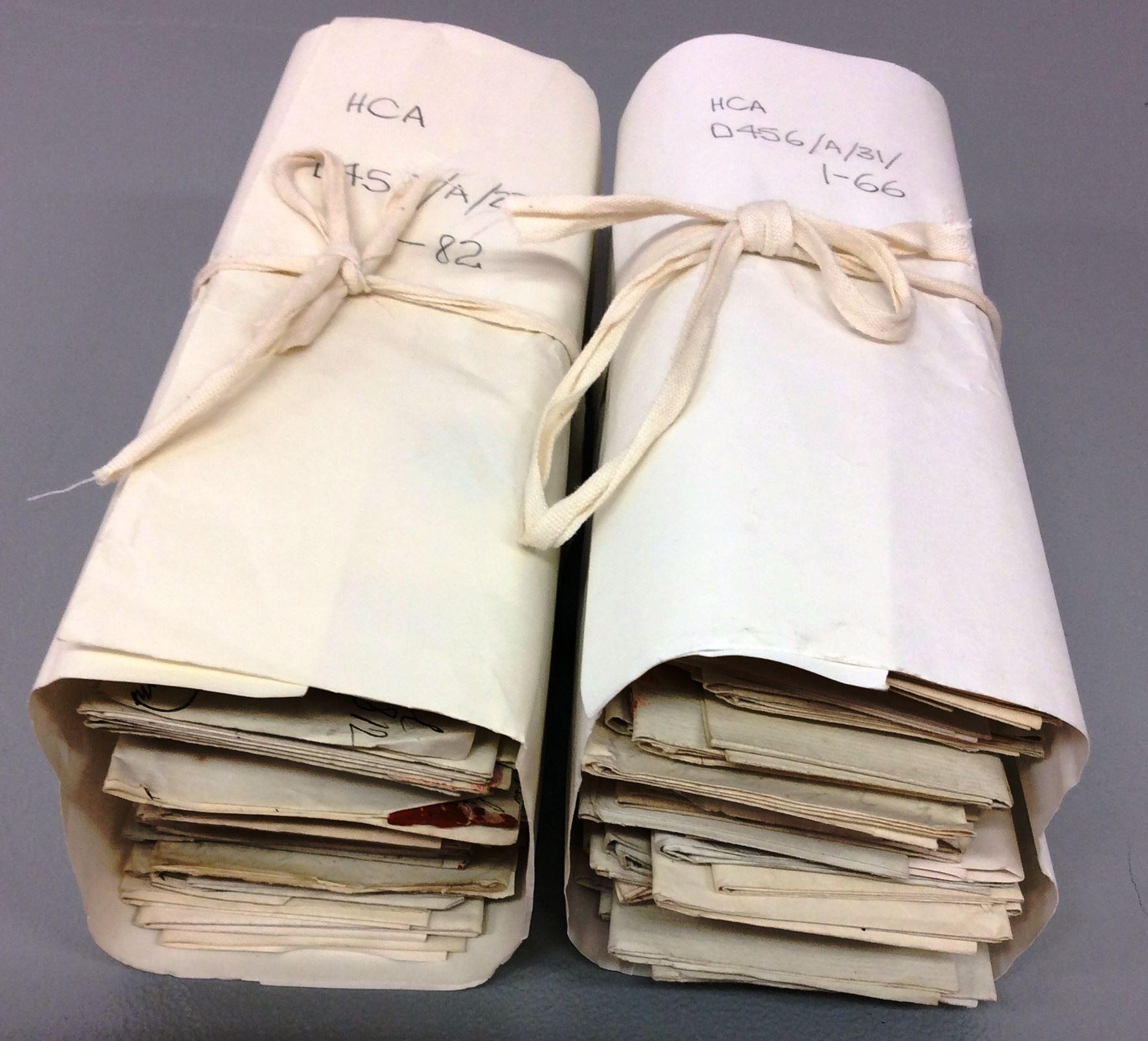 Two bundles of letters wrapped in acid-free cream coloured paper and tied with archival tape