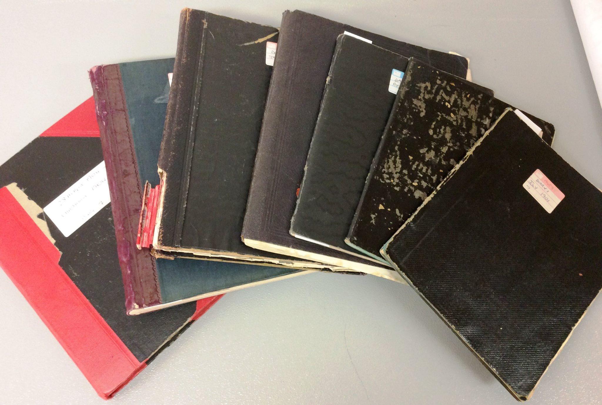 Seven closed books with dark covers shown fanned out