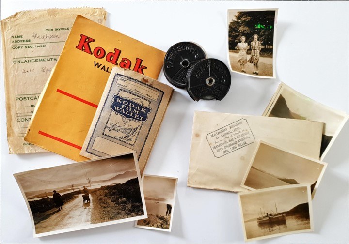 On a white background sit an array of archival items: a yellow Kodak leaflet, two rolls of microfilm, several photographs and a number of letters