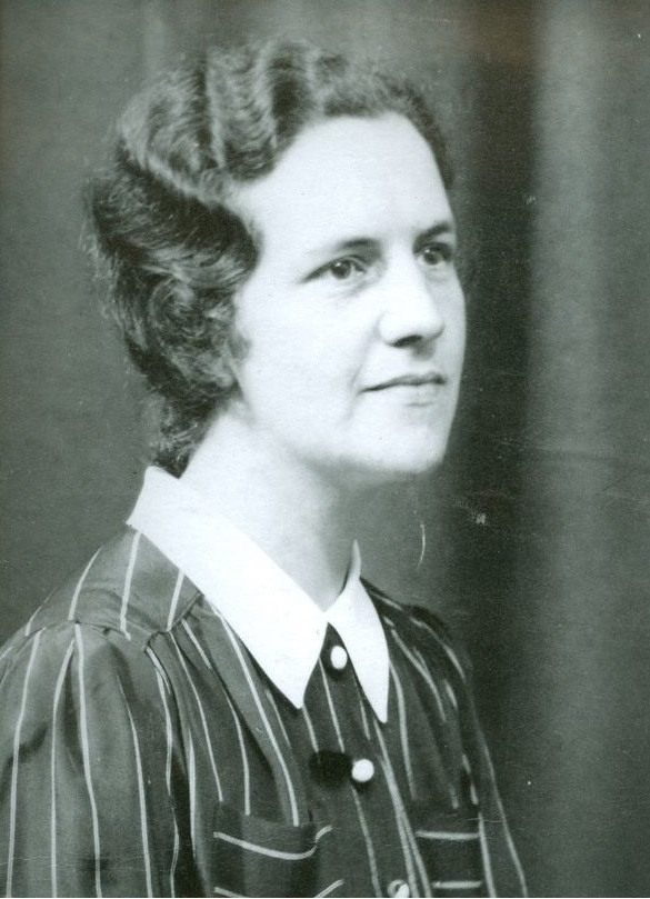 Black-and-white portrait of a woman wearing a striped blouse with a white pointed collar and dark buttons, posed against a plain backdrop.