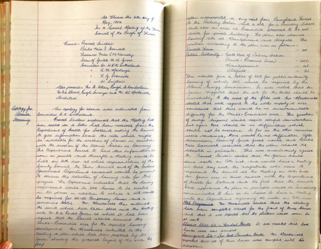 Open ledger showing handwritten meeting minutes in blue ink about UKAEA housing, dated May 1954.