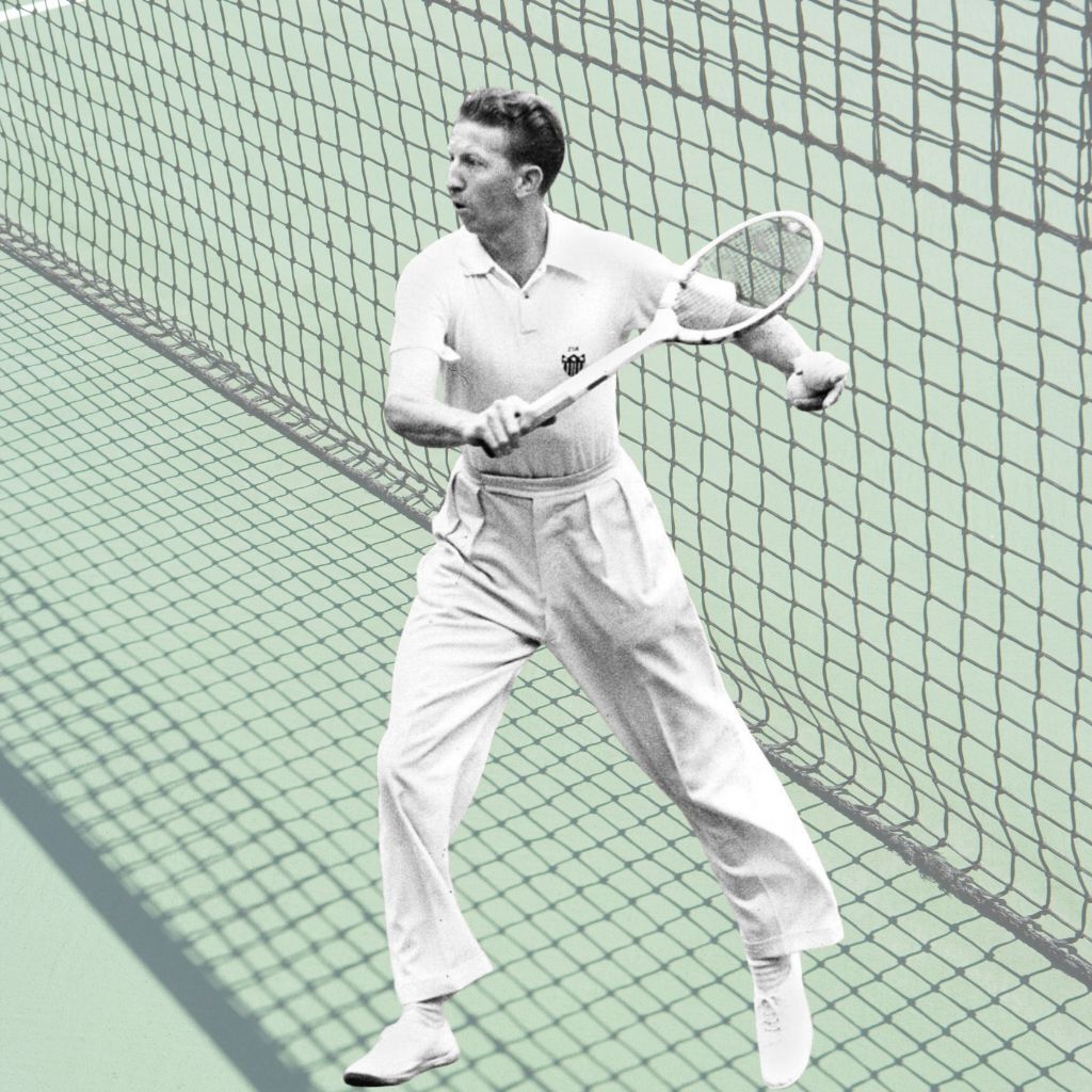 An image of a tennis player standing near the net on a court, holding a racquet in both hands and preparing for a shot. The player wears a short‑sleeved polo shirt, high‑waisted trousers, and tennis shoes. A large net stretches diagonally across the background.