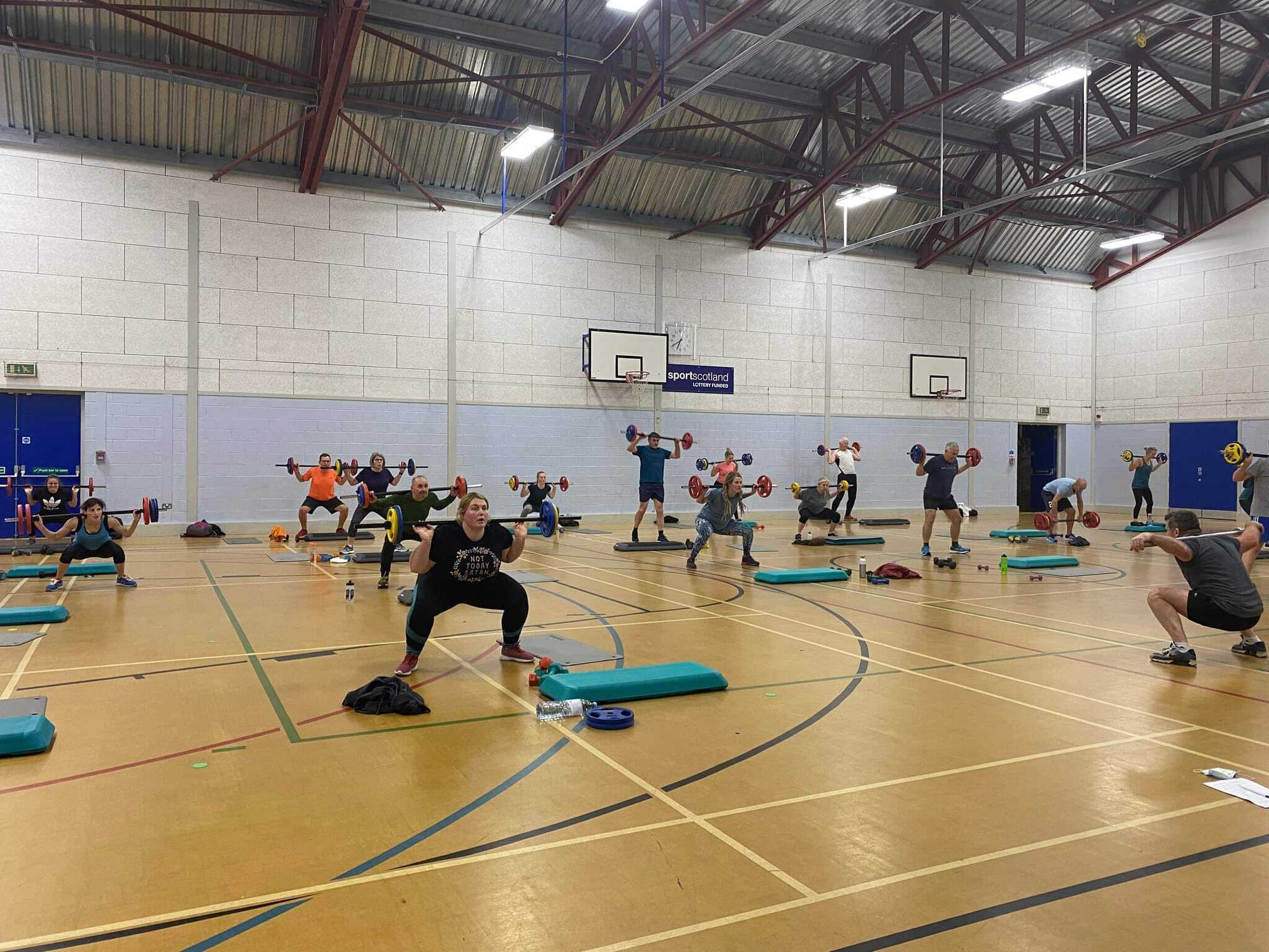 Inside a sports hall as participants are in the middle of a barbell workout.