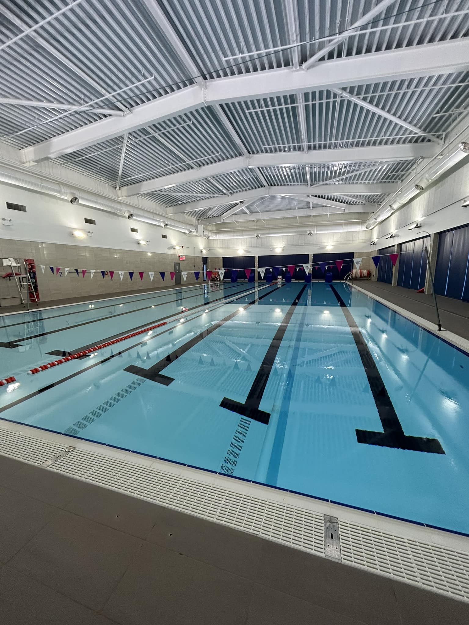 Indoor swimming pool with lane dividers and overhead flags.