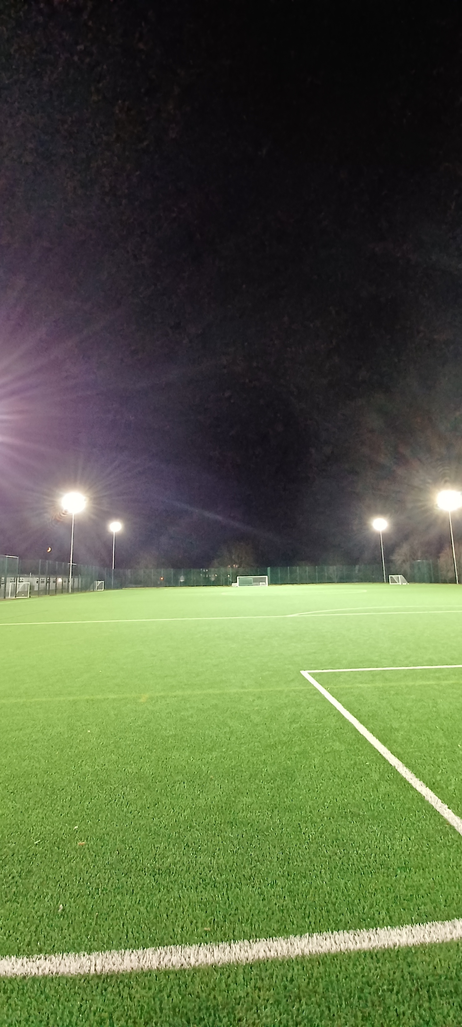 Football pitch at night lit by floodlights.
