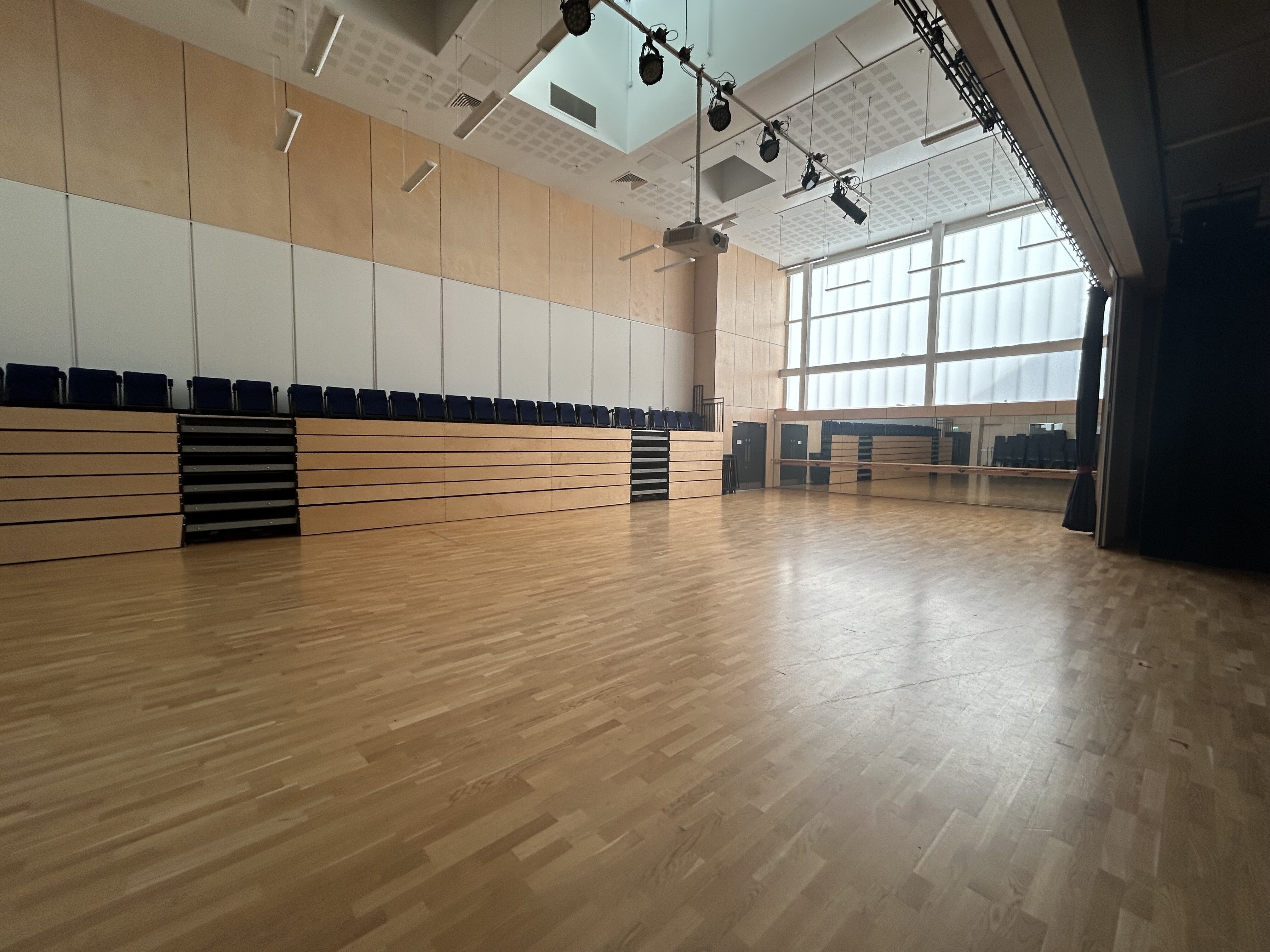 A bright, spacious dance studio with seating available.