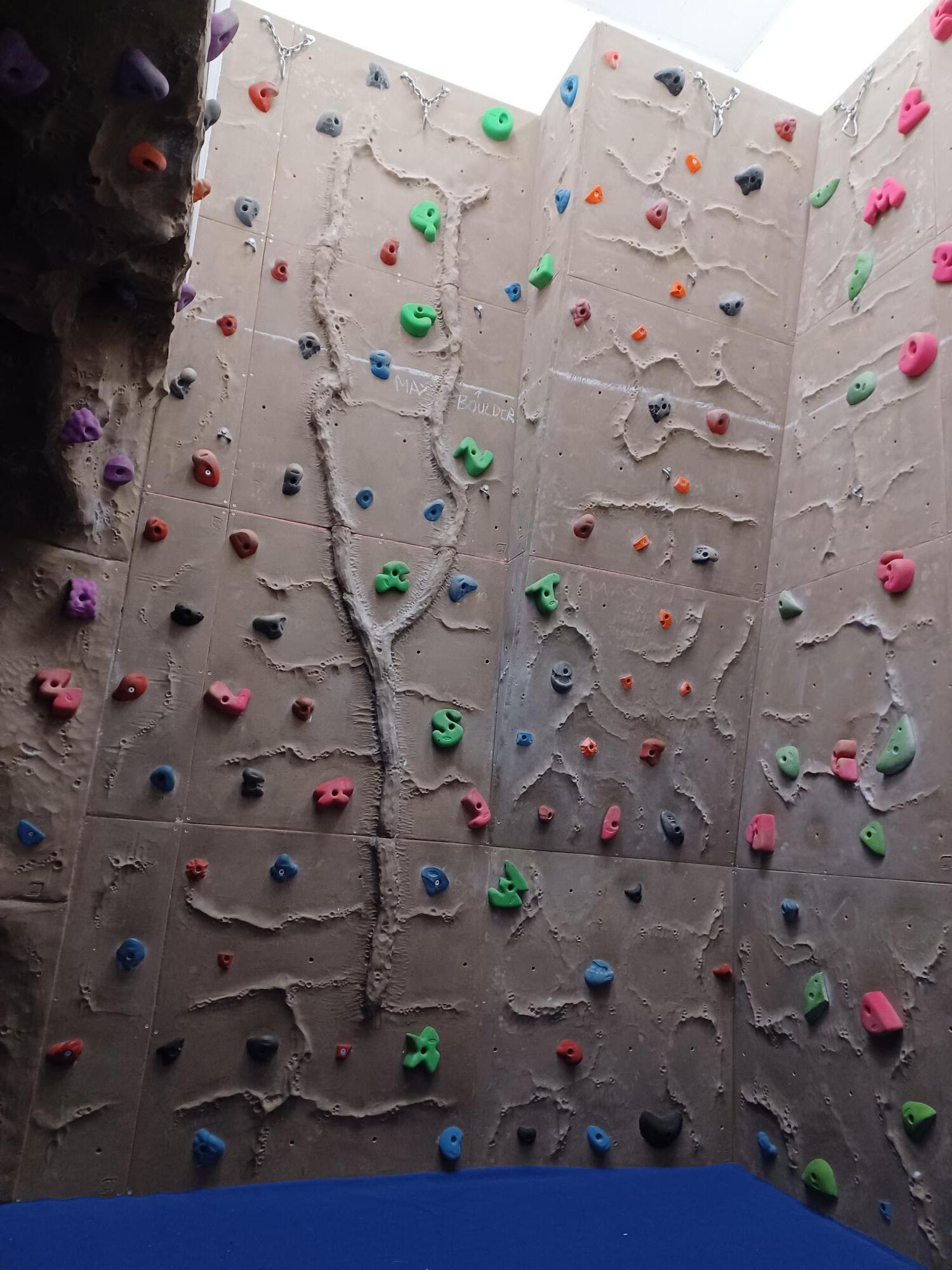 An indoor climbing wall with colourful climbing holds arranged across textured panels.