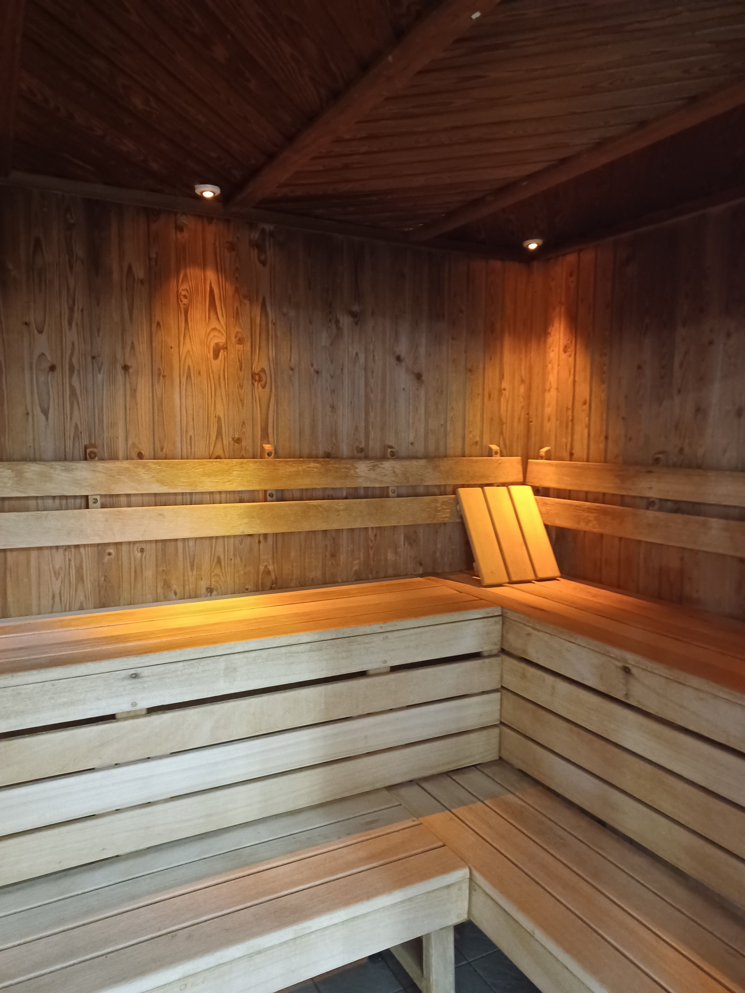 A wooden sauna room with warm lighting and tiered bench seating along the walls.