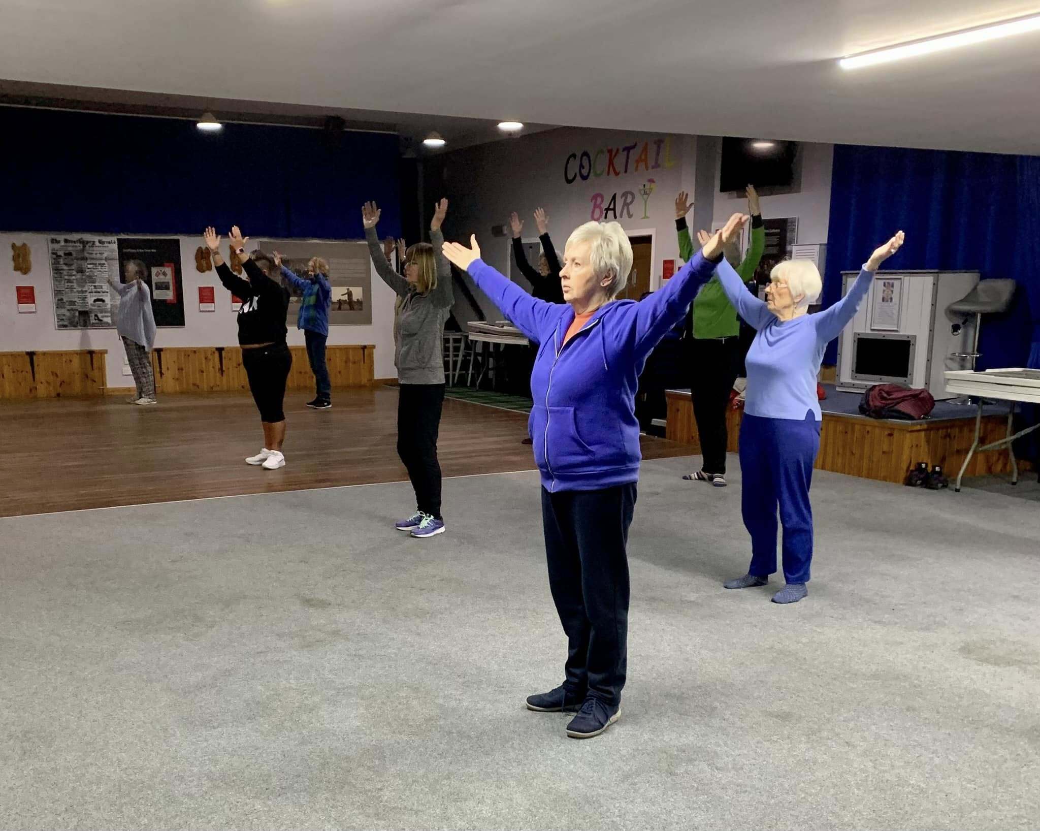 Tai Chi class practising an arm-raise movement together