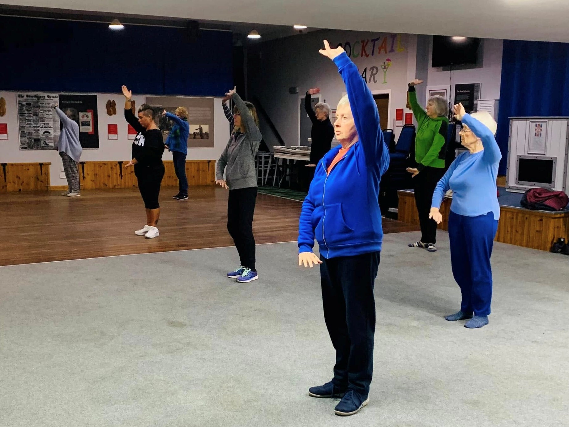 Tai Chi participants holding an overhead arm movement in class