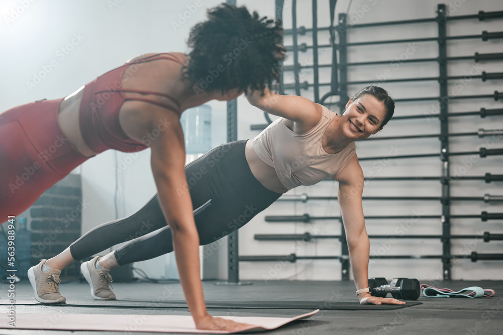 Two people holding a side plank position in a gym, facing each other during a workout.