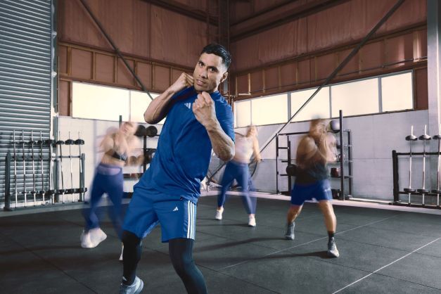 A group fitness class practising martial arts–style movements in a gym, with the instructor leading punches and footwork.