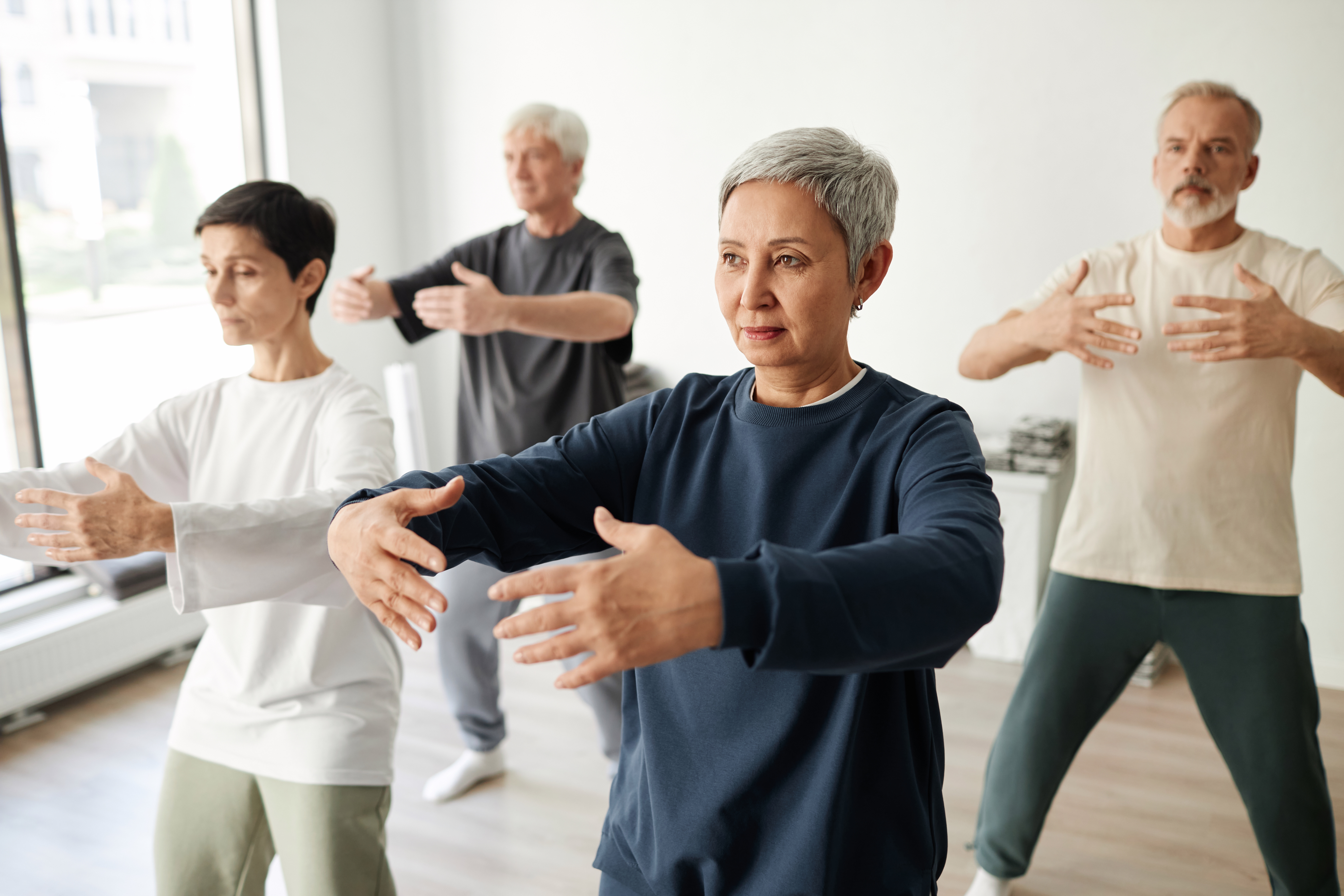 Group practising Qi Gong arm movements together in a studio