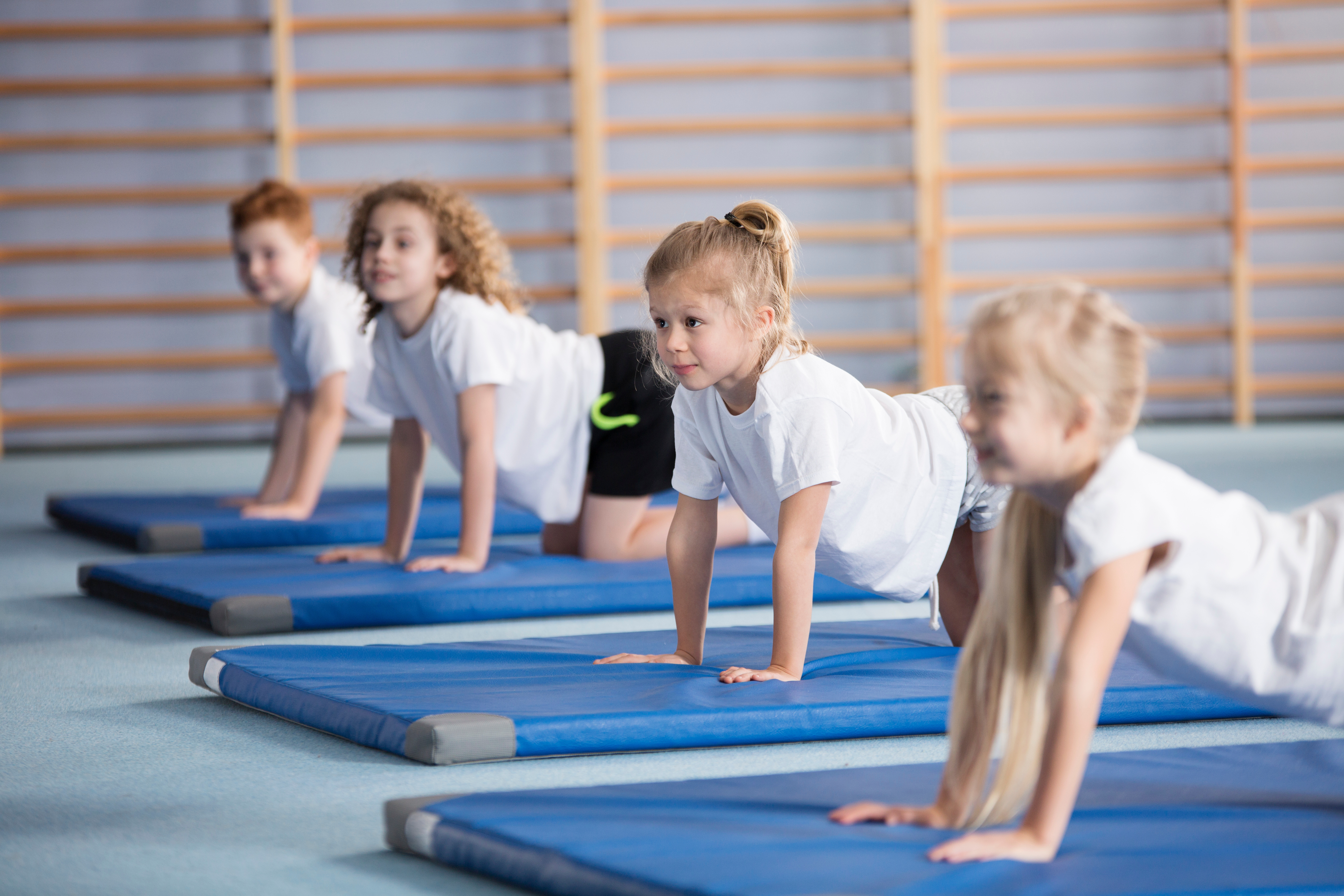 Children on their hands and knees on fitness mats.