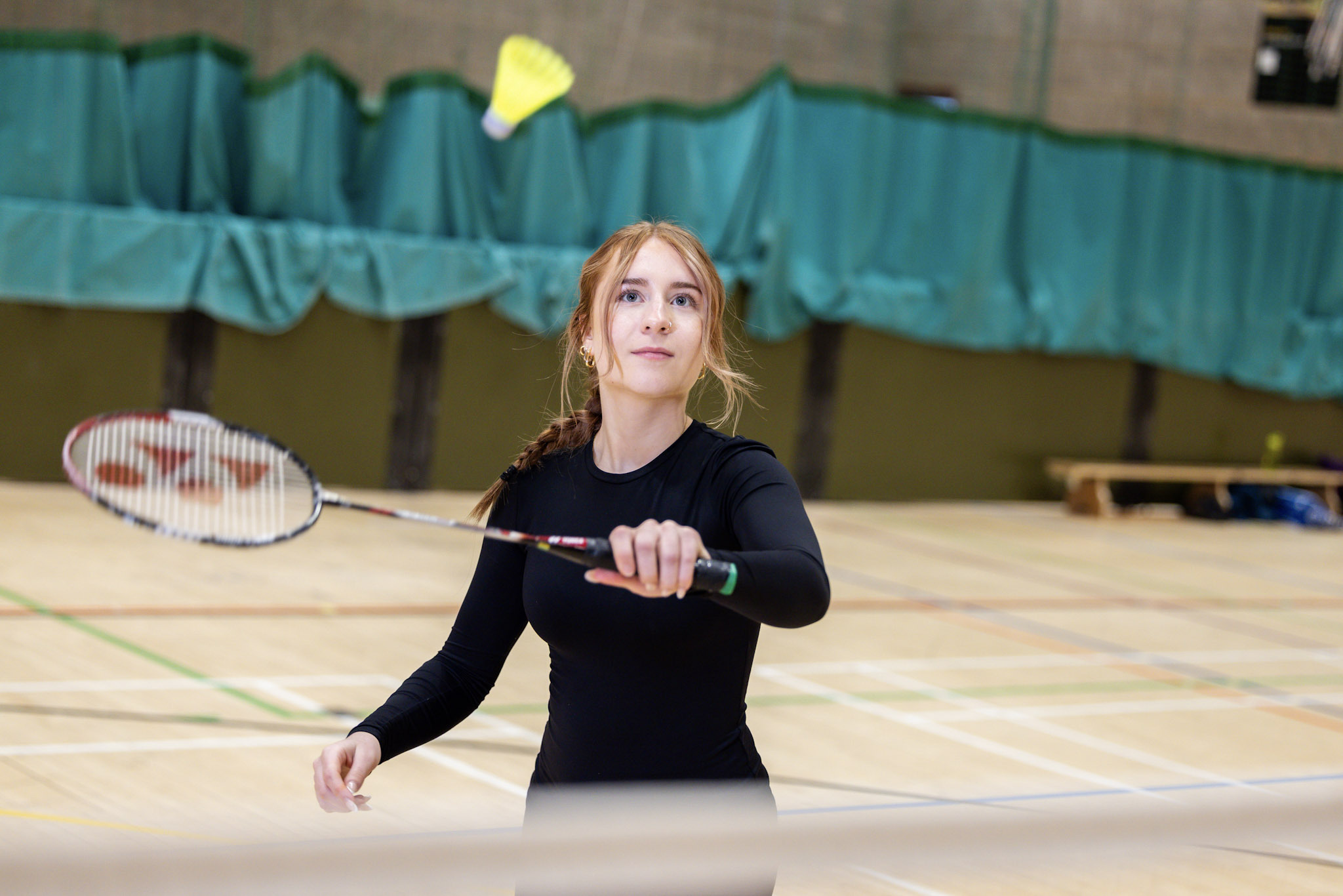 Close-up of a woman about to hit a badminton shuttlecock at Inverness Leisure