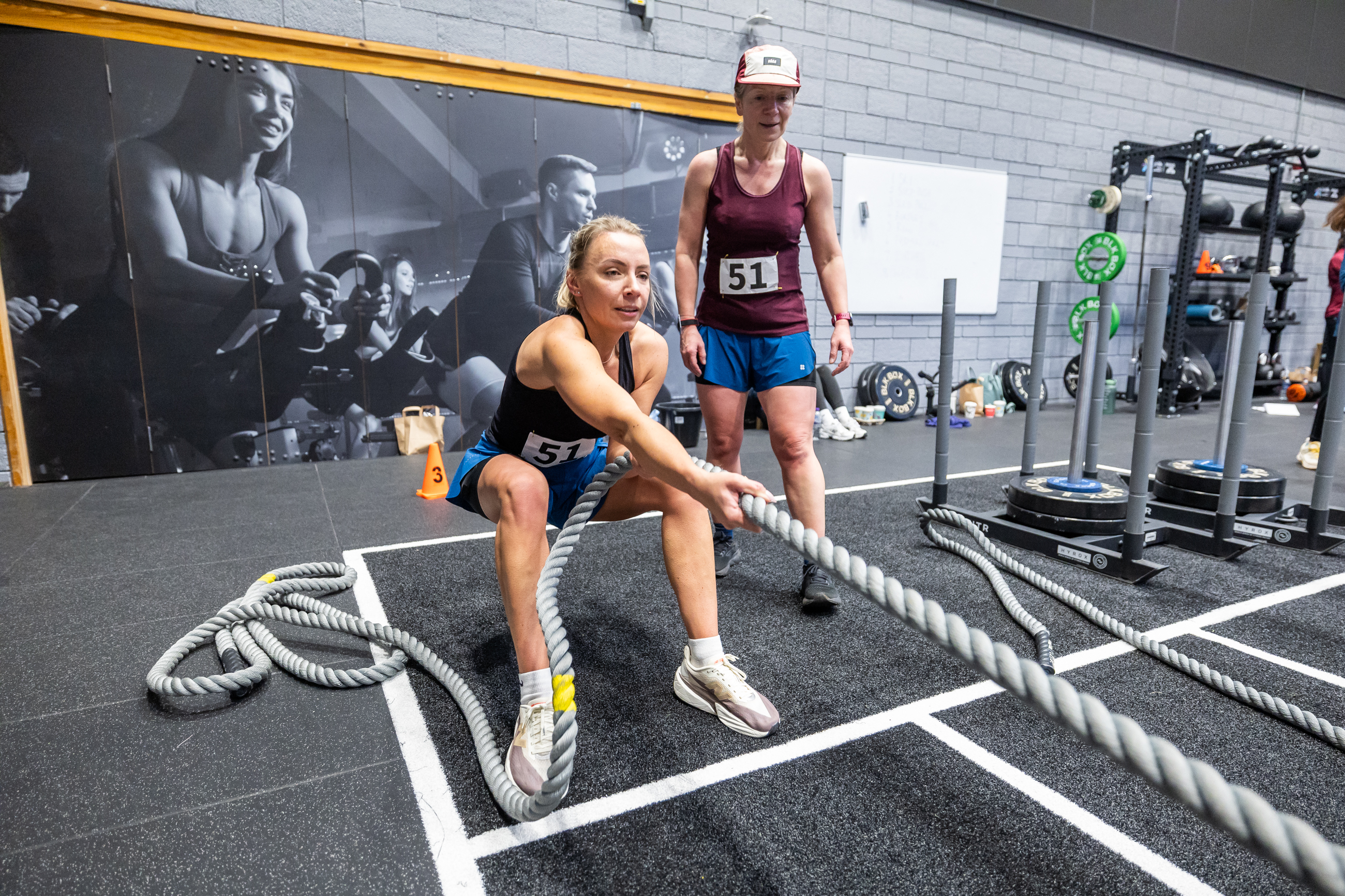 Two women performing a rope sled pull at the Inverness Leisure HYROX studio