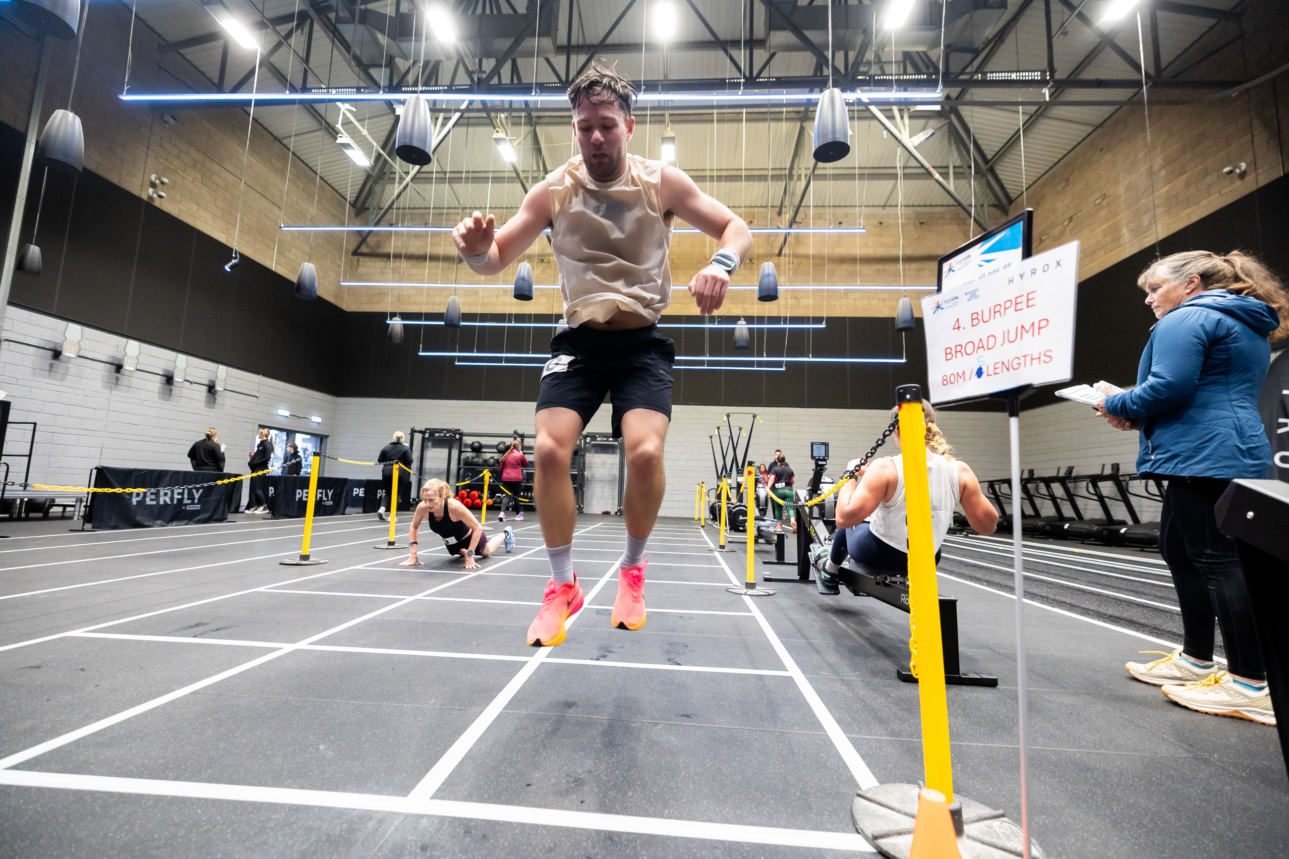 Man mid-air during a burpee broad jump exercise, HYROX studio Inverness Leisure