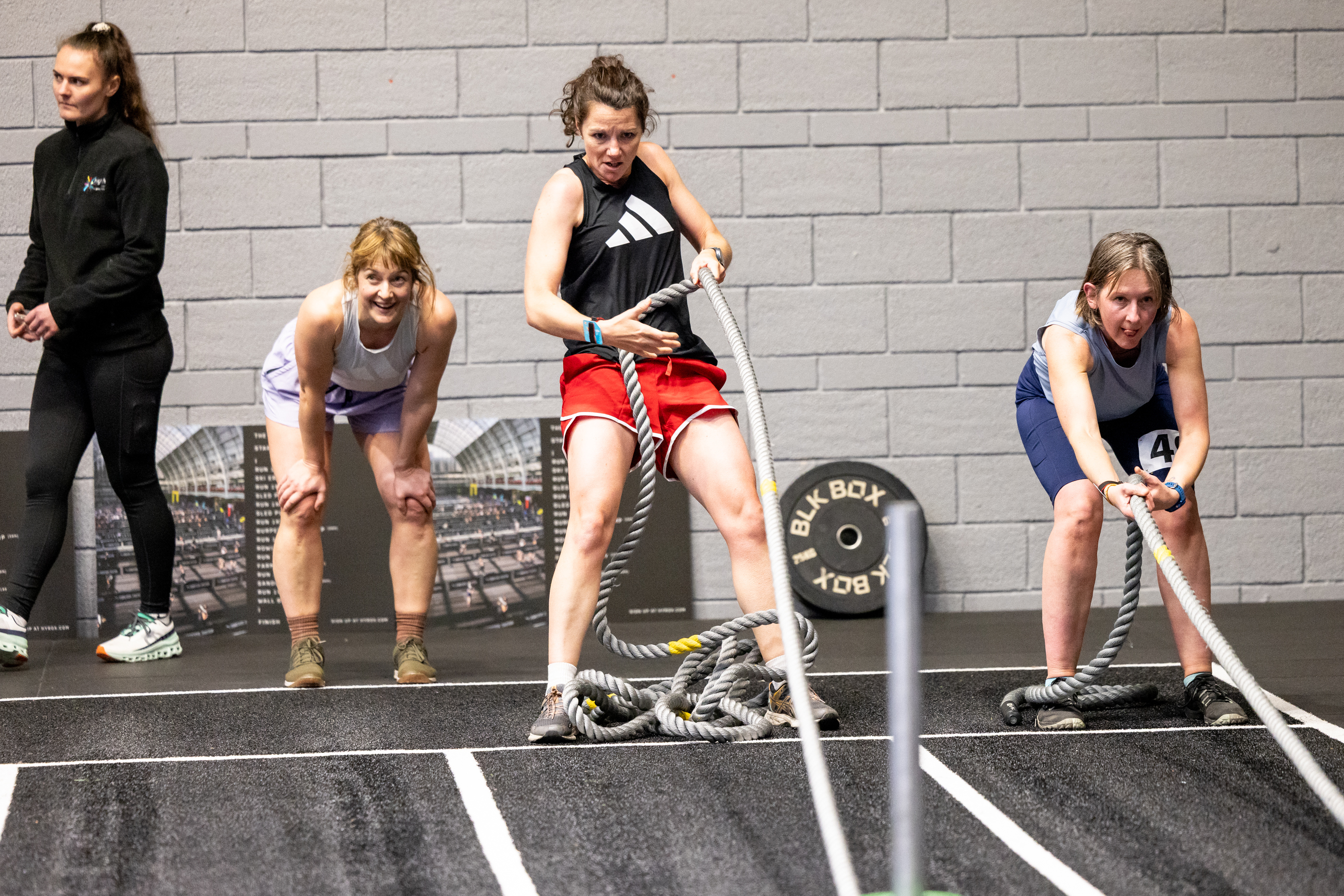 People pulling battle ropes during a fitness competition in an indoor gym setting.