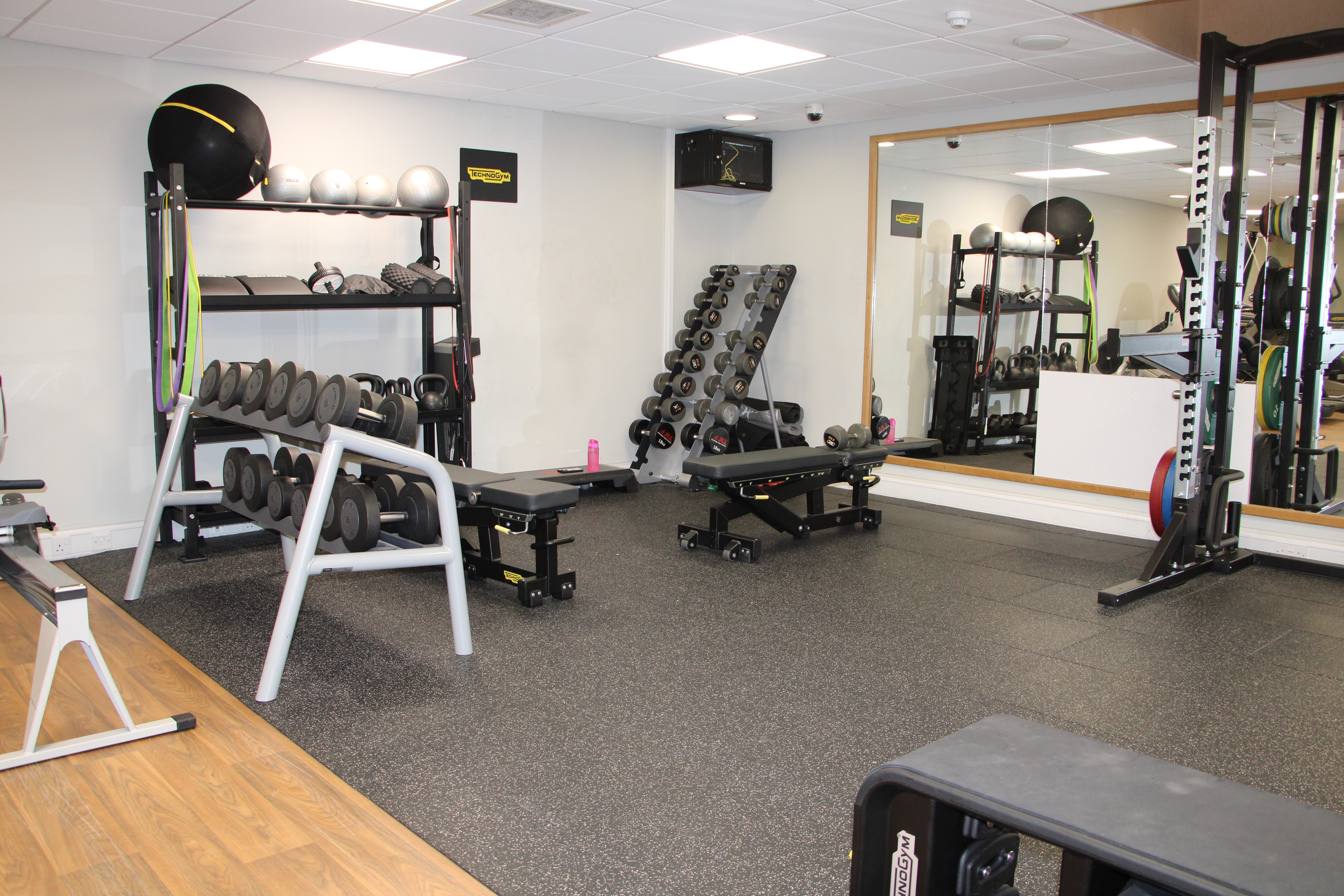 Gym with a mirrored wall and various gym equipment.