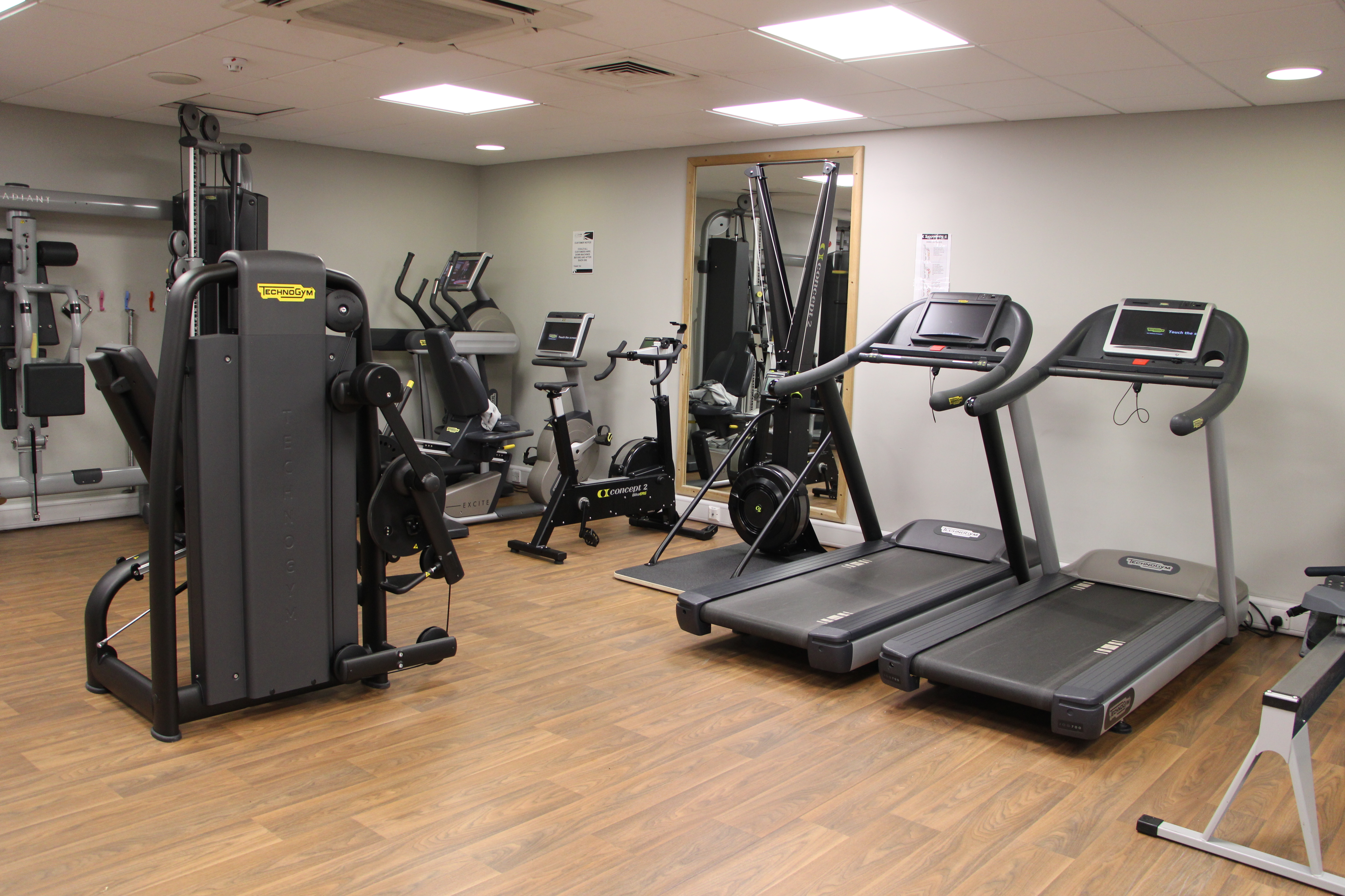 Gym with a mirrored wall and various gym equipment.