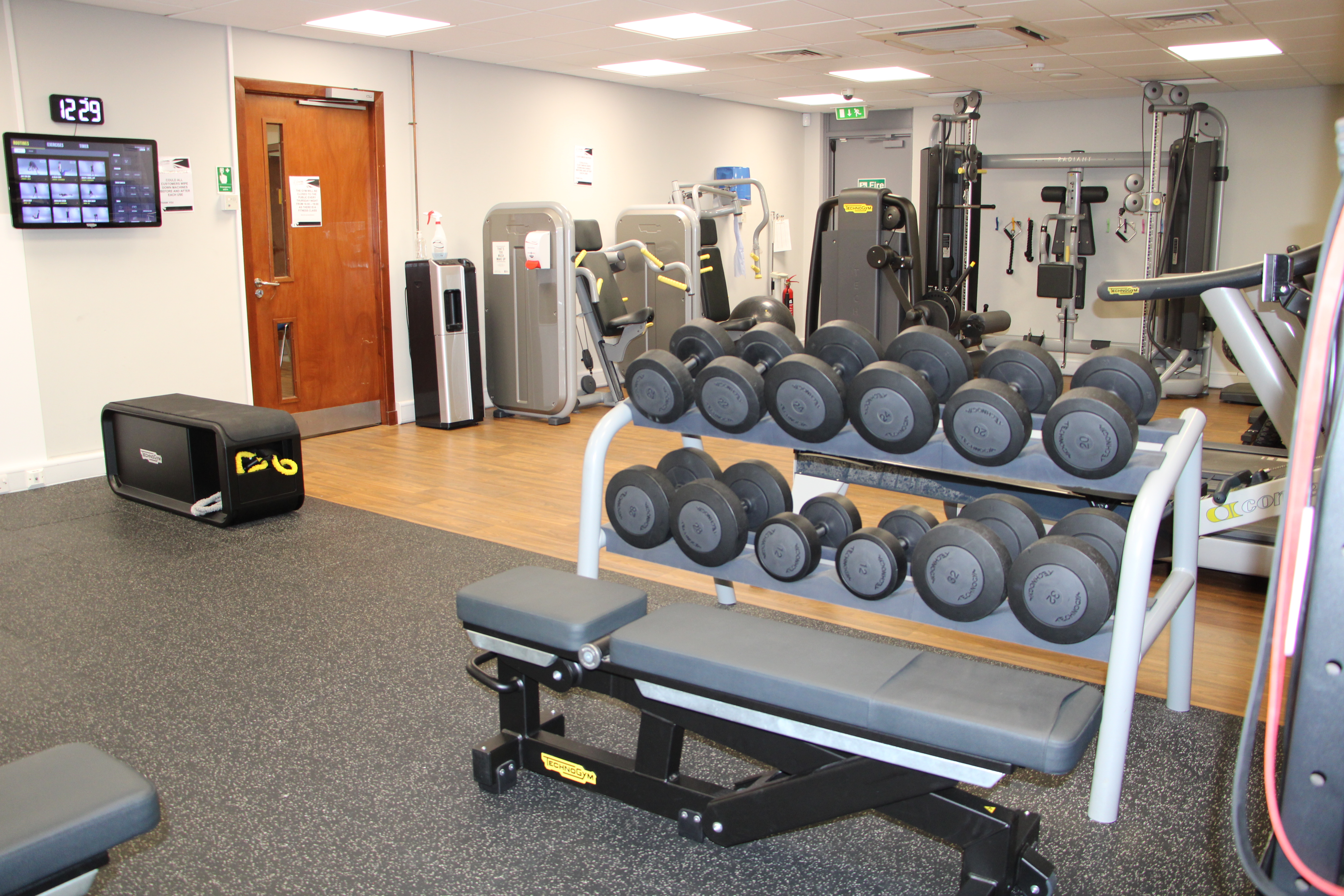 Gym with a mirrored wall and various gym equipment.