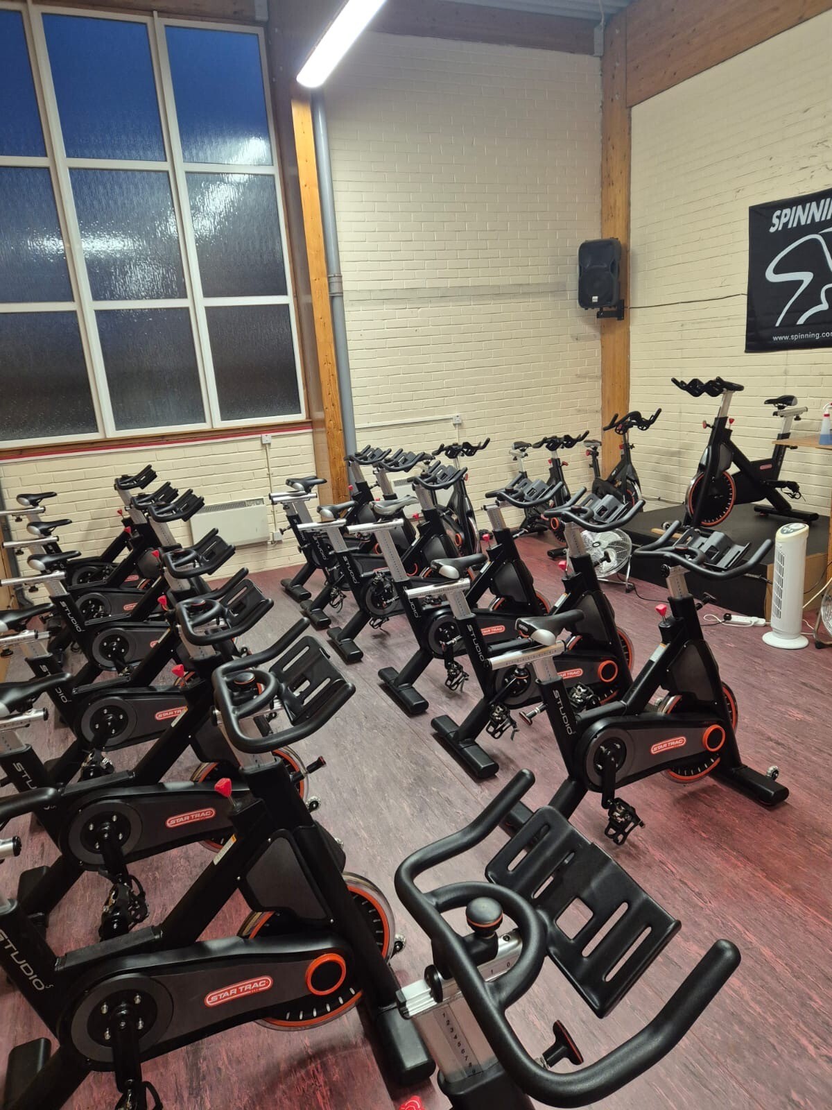 Hall with a large window and equipped with indoor cycling bikes set up for a class.