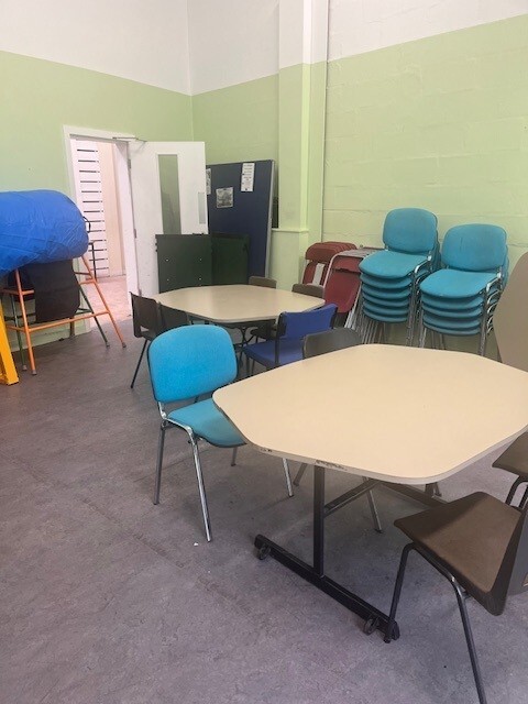 Well-lit room equipped with meeting room tables and chairs.