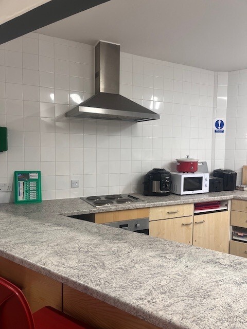 Kitchen featuring worktops, a hob with extraction fan, a microwave oven and kettle.