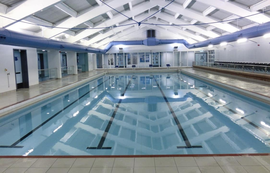 A swimming pool situated beneath a bright, arched ceiling, complete with designated swim lanes.