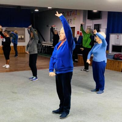 Tai Chi participants holding an overhead arm movement in class
