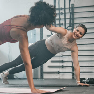 Two people holding a side plank position in a gym, facing each other during a workout.