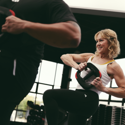 People taking part in a core strength class, lifting weight plates while balancing on one leg inside a gym studio.
