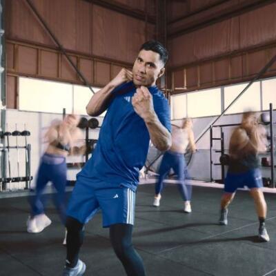A group fitness class practising martial arts–style movements in a gym, with the instructor leading punches and footwork.