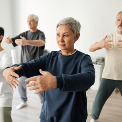 Group practising Qi Gong arm movements together in a studio