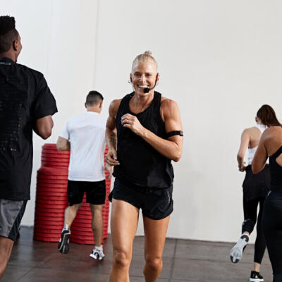 People running and exercising together in a group fitness class inside a gym studio.