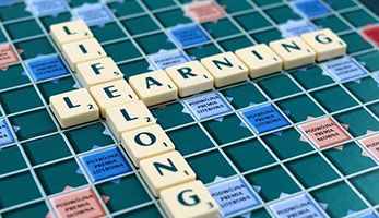 Scrabble board with two lines of letters spelling Lifelong and Learning