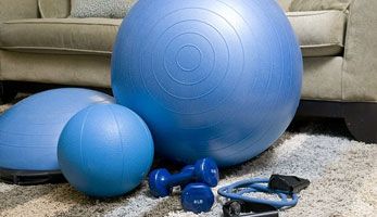 Home workout equipment in a living room, large and small excercise ball, hand weights and skipping rope